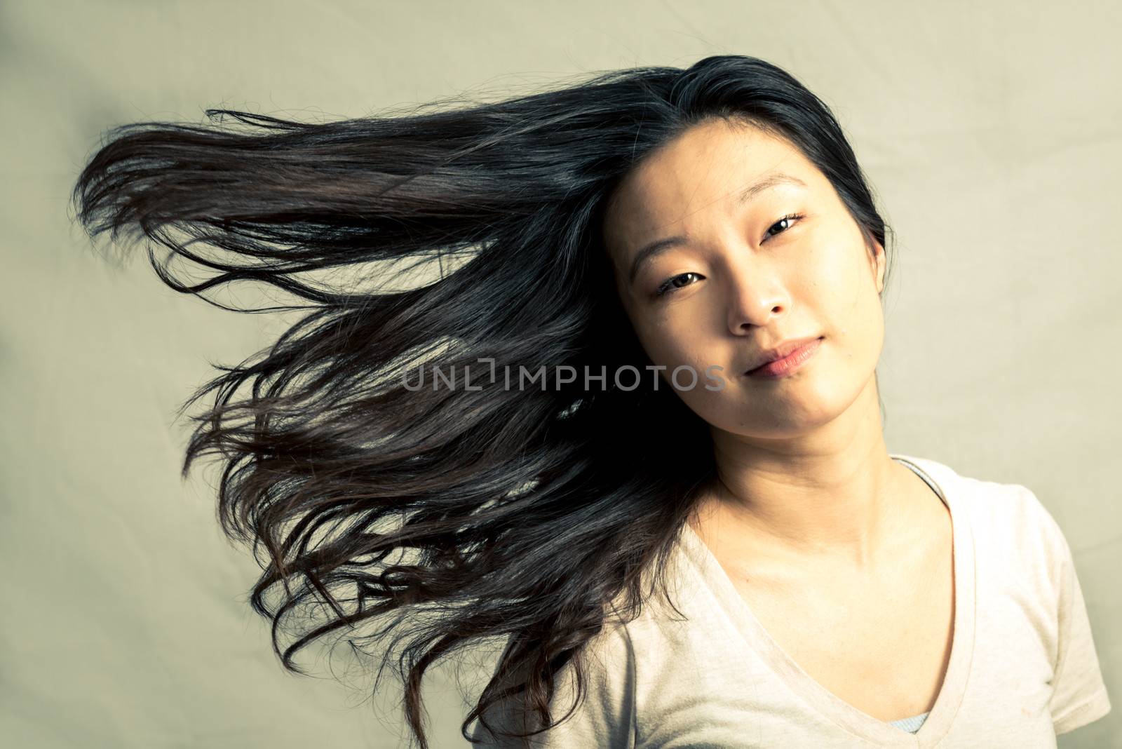 Young woman flicking her hair and posing, with fashion tone and background