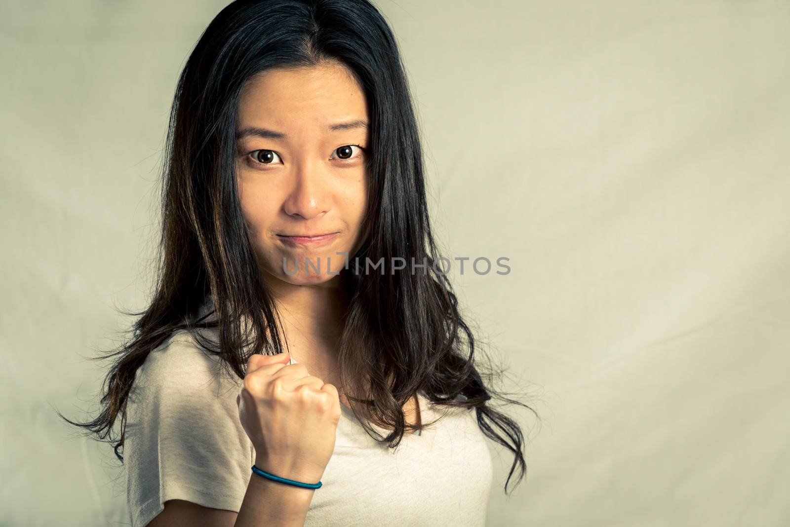 Young woman clenching her fist for encouragement, with fashion tone and background