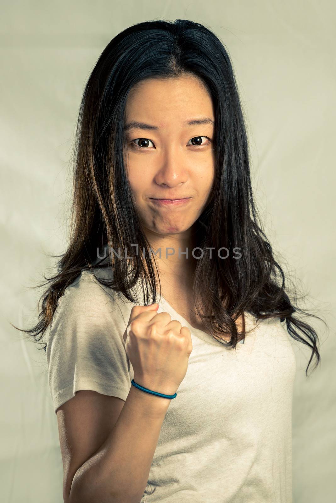 Young woman clenching her fist for encouragement, with fashion tone and background