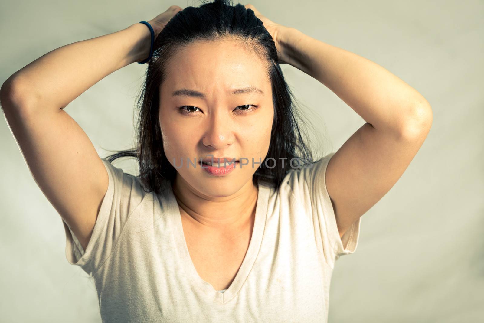 Young woman pulling her hair looking frustrated, with fashion tone and background