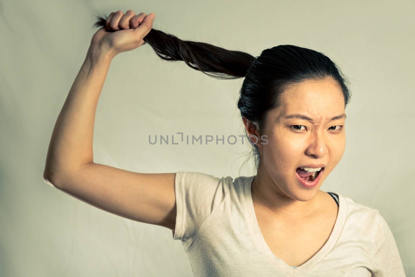 Young woman pulling her hair looking frustrated, with fashion tone and background