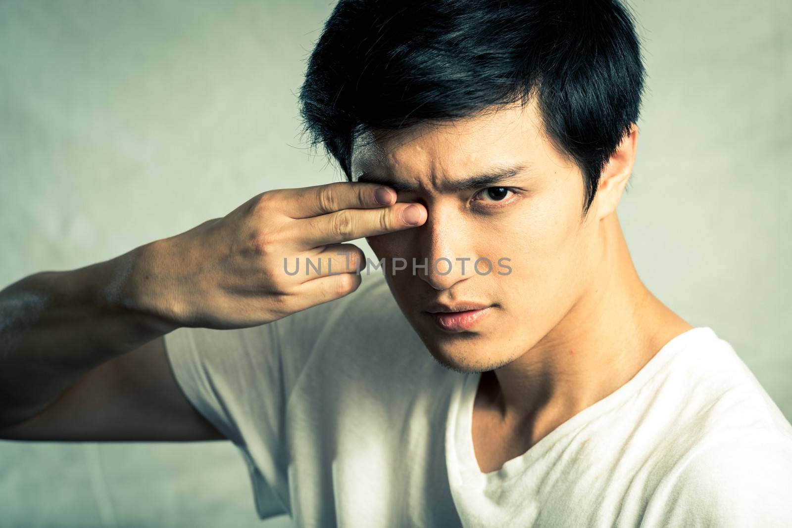 Young man posing with two fingers covering one eye, with fashion tone and background