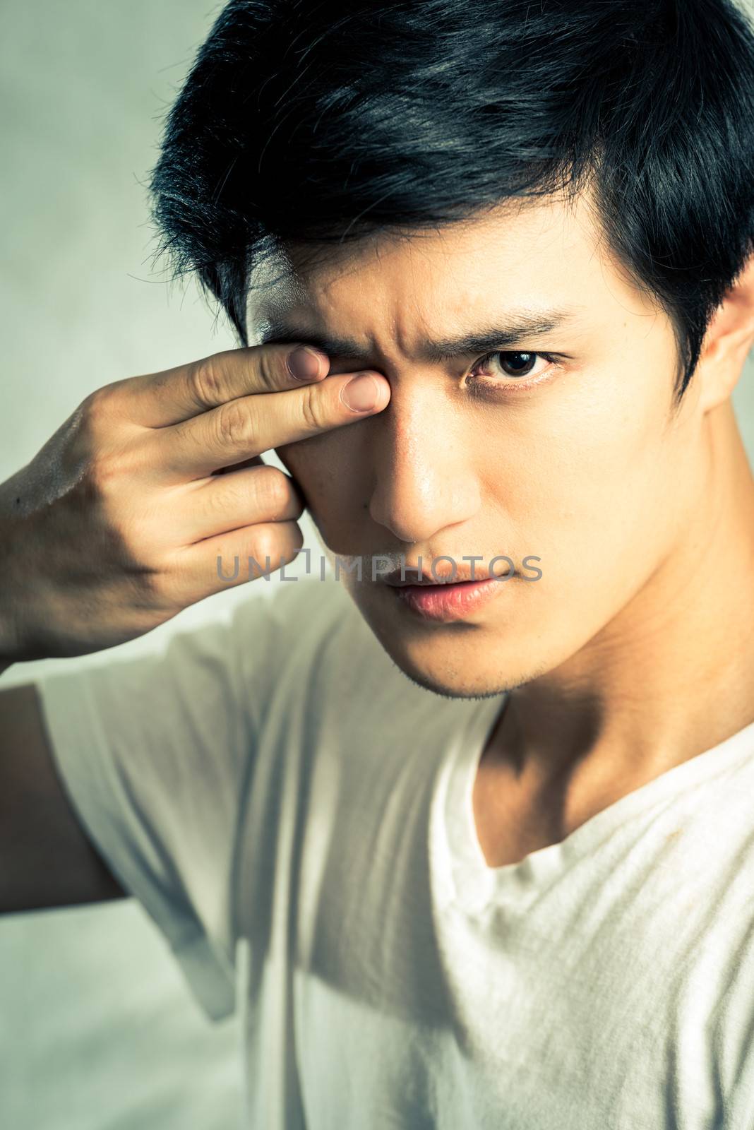 Young man posing with two fingers covering one eye, with fashion tone and background