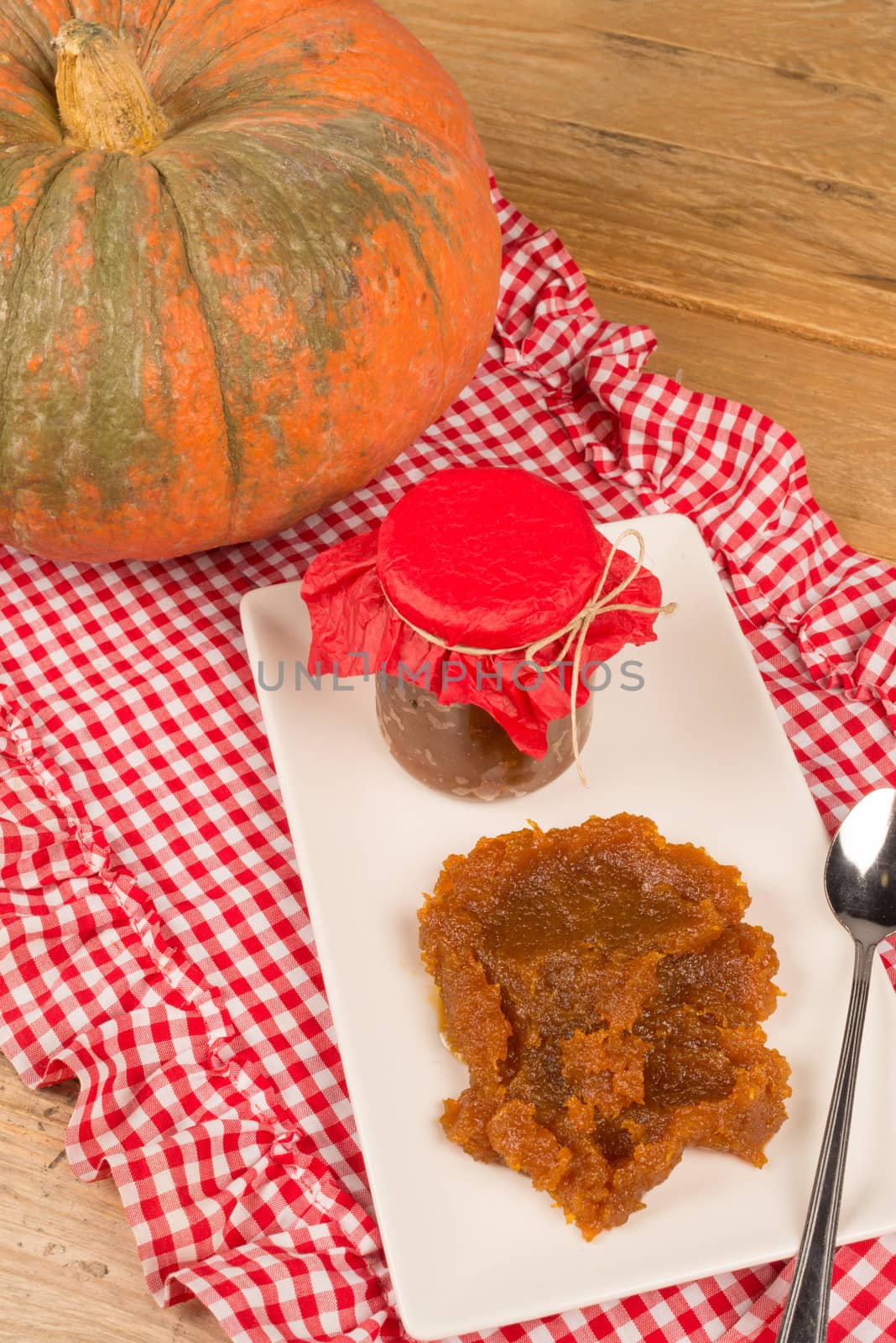 Jar of homemade pumpkin jam with its main ingredient