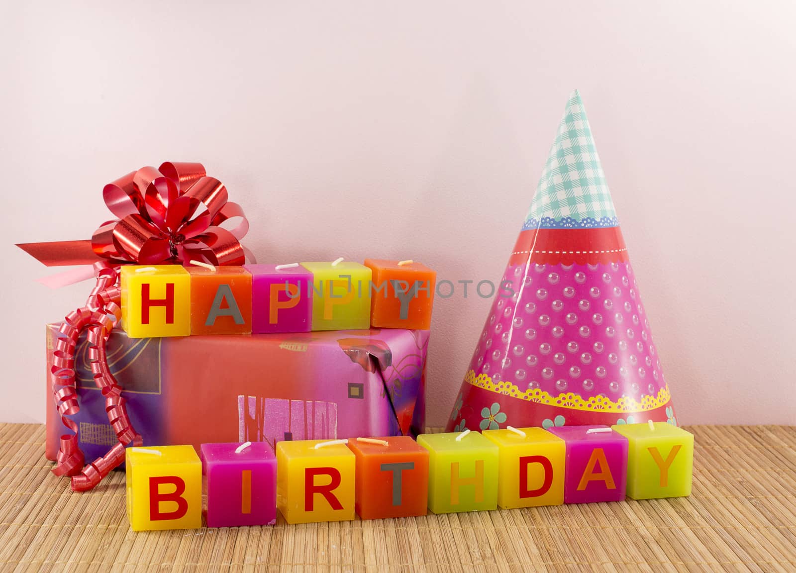 happy birthday candles with present and pink wallpaper