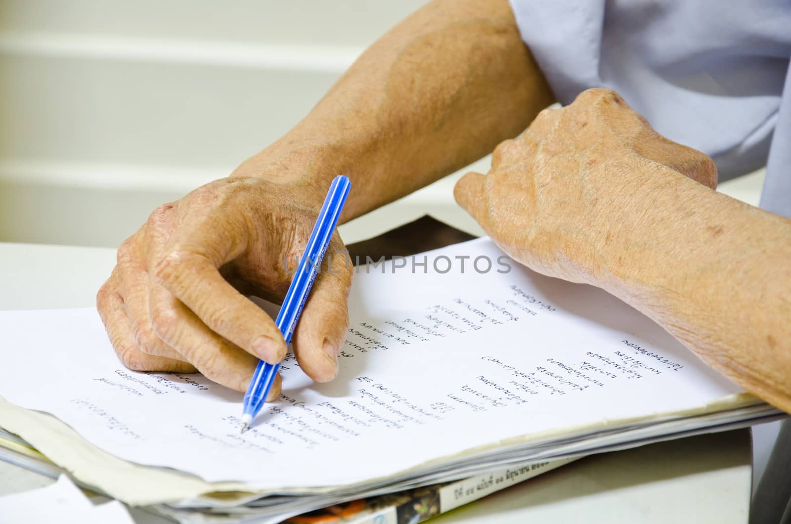 Hand of old man writing with pen