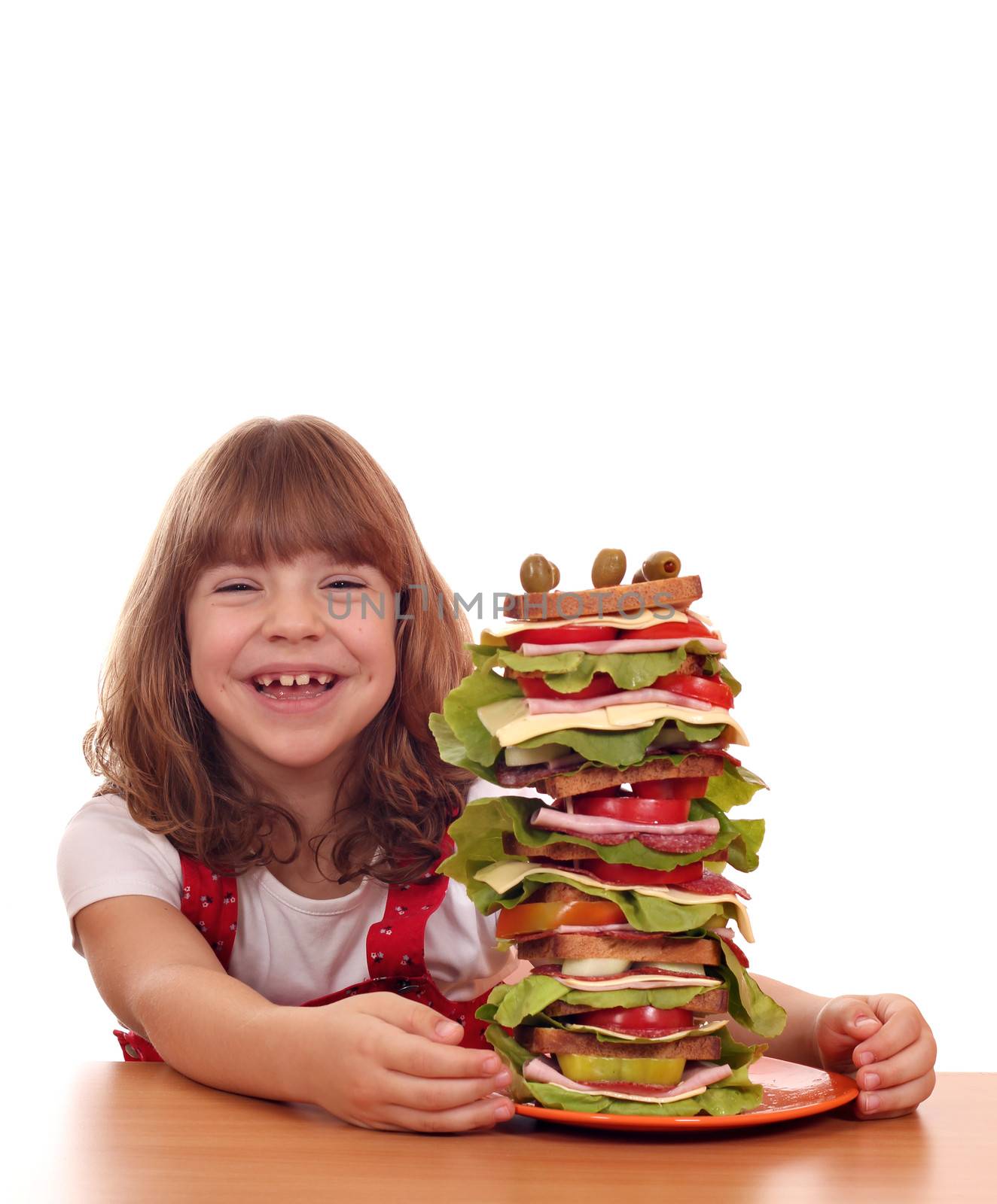 happy little girl with tall sandwich on table by goce