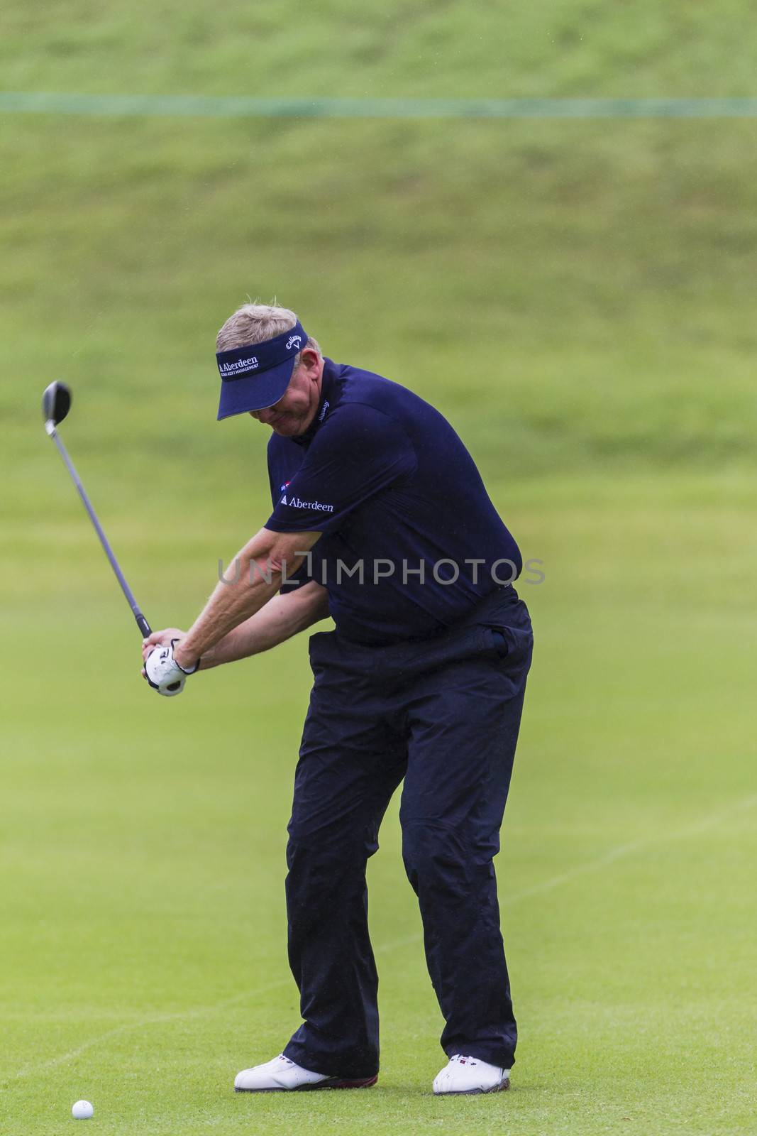 Close up telephoto action of professional golf pro player swinging to  hit ball off fairway at Durban Country Club Volvo Tournament.