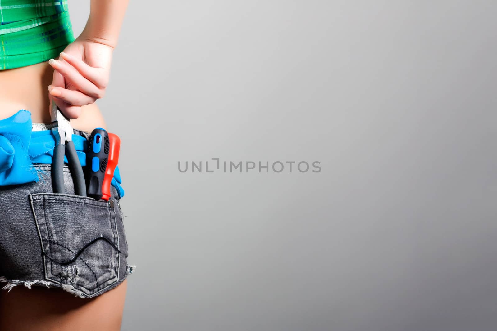 portrait of female worker with pliers and screwdrivers in back pocket