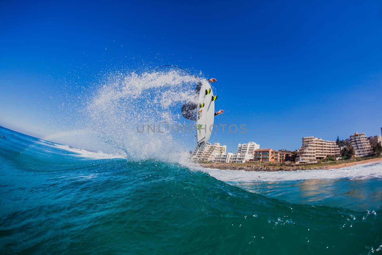 Water perspective of surfer doing air maneuver off ocean wave lip.