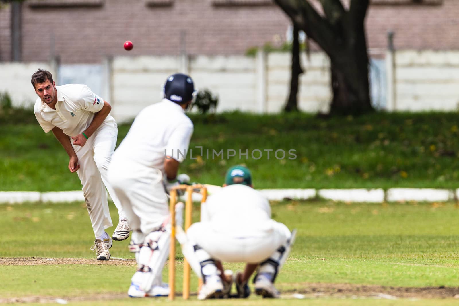 Spin bowler flights ball to batsman with wicket keeper close to stumps in a local match league fixture.