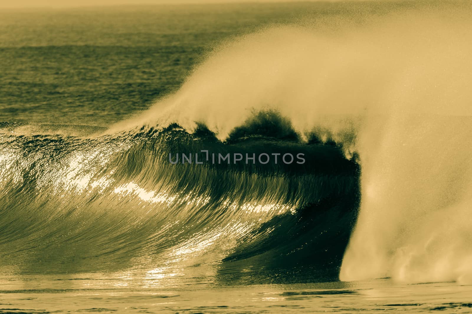 Large hollow curling ocean wave crashing on shallows in a cross process for mood contrasts