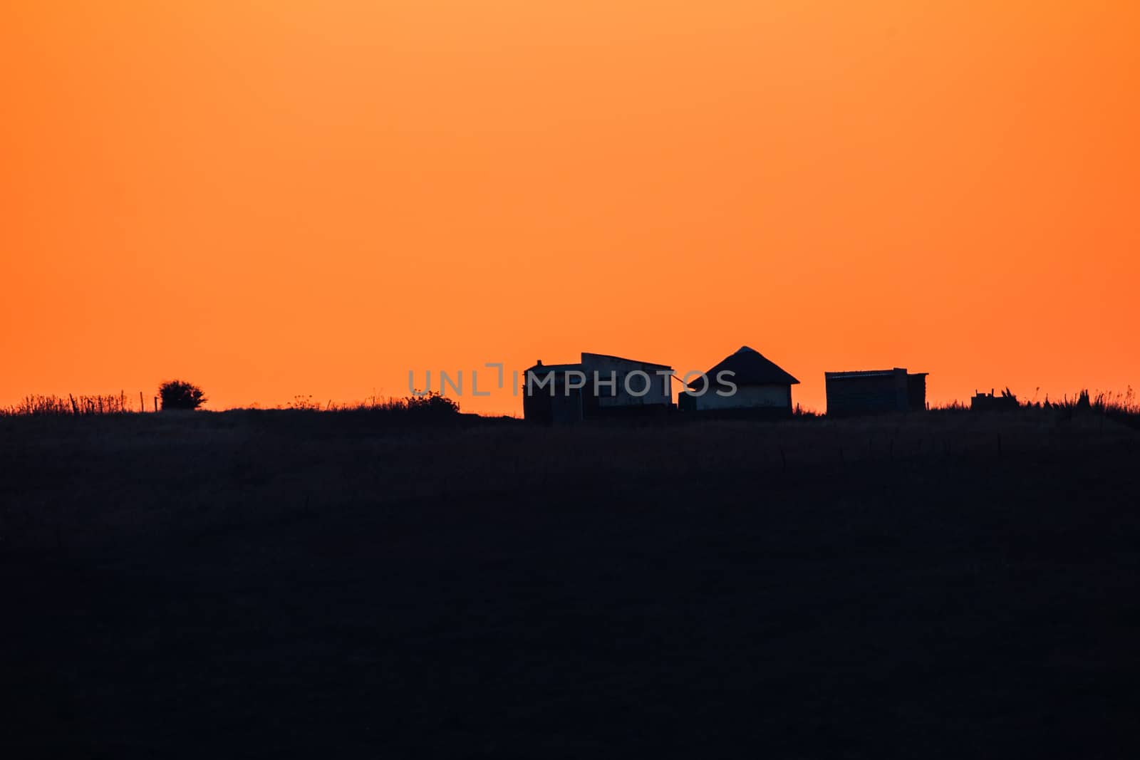 African Morning dawn light upon a distant hill african home outlined silhouetted in color.