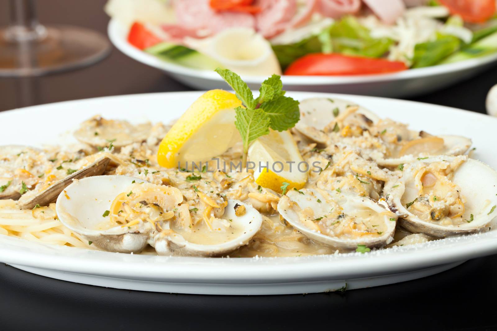 Italian pasta dish with fresh clams over pasta with herbs and cheese.  Shallow depth of field.