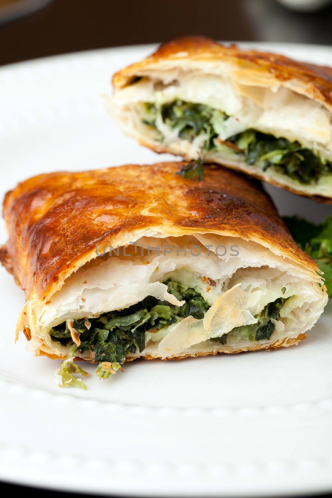 Greek spanakopita or spinach pie on a white plate.  Shallow depth of field.