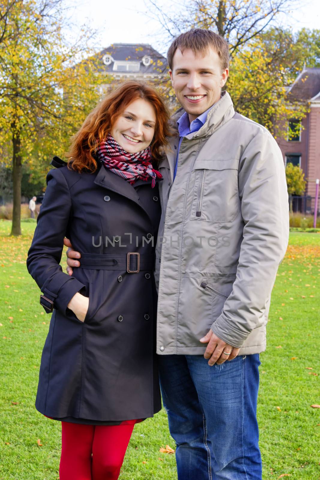 Outdoor happy couple in love posing against autumn Amsterdam bac by Tetyana