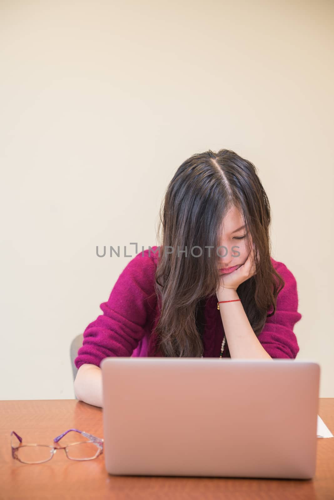 Young woman reading a book behind a laptop