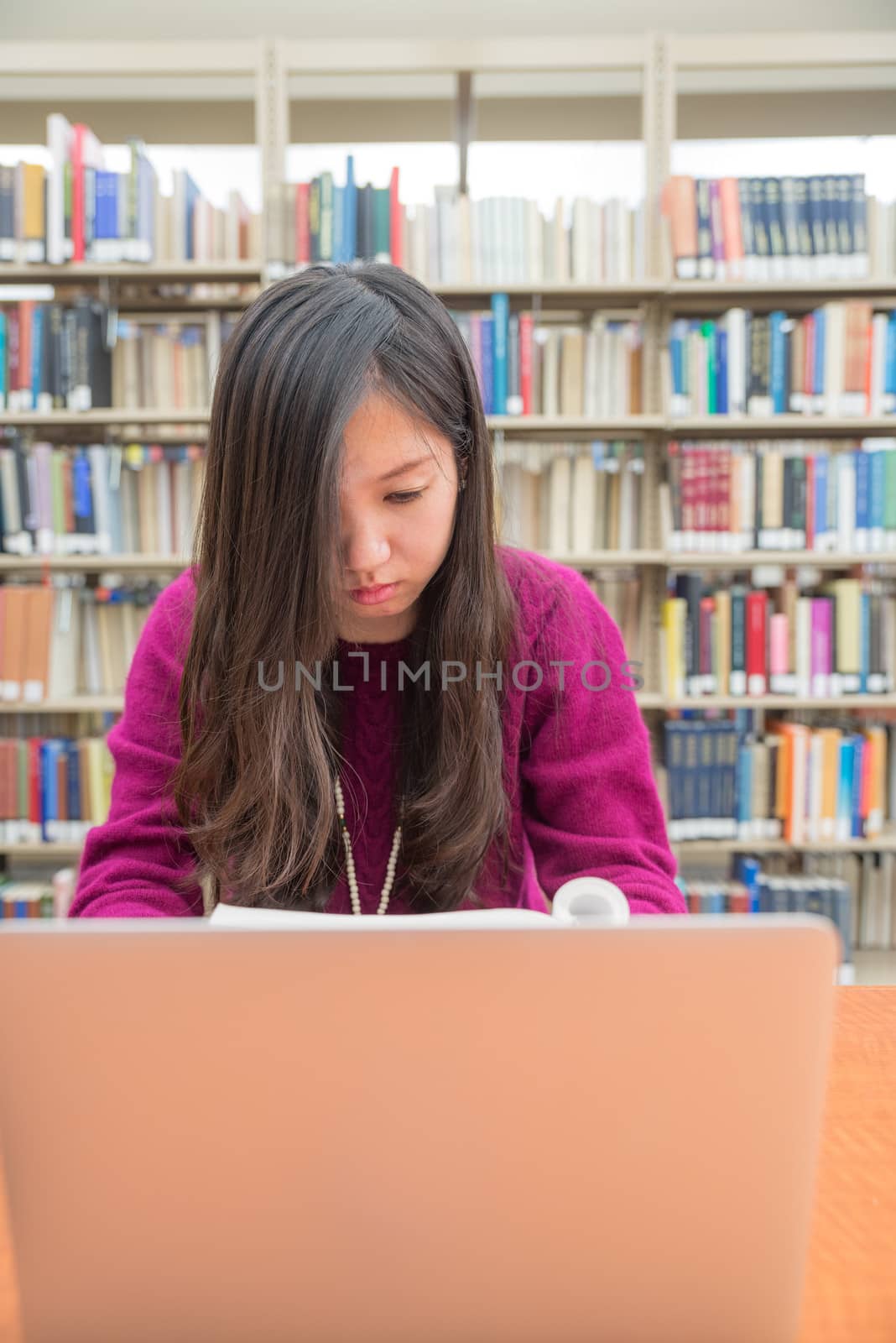 Woman with book and laptob studying in library