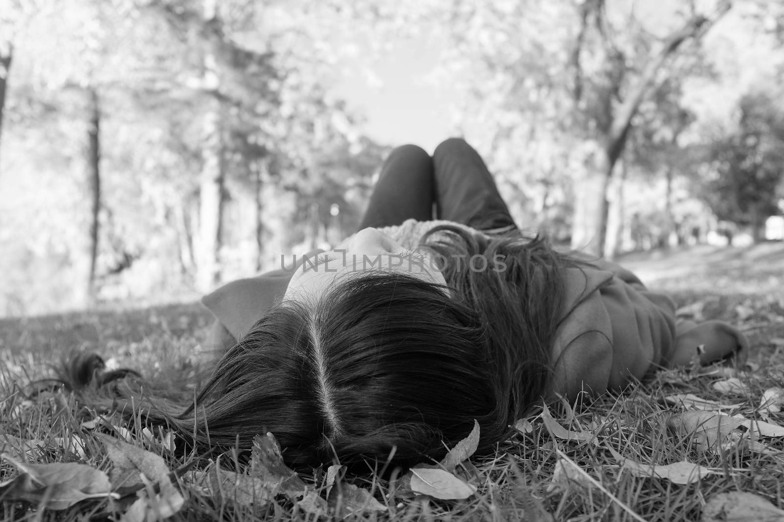 Woman laying on grass by IVYPHOTOS