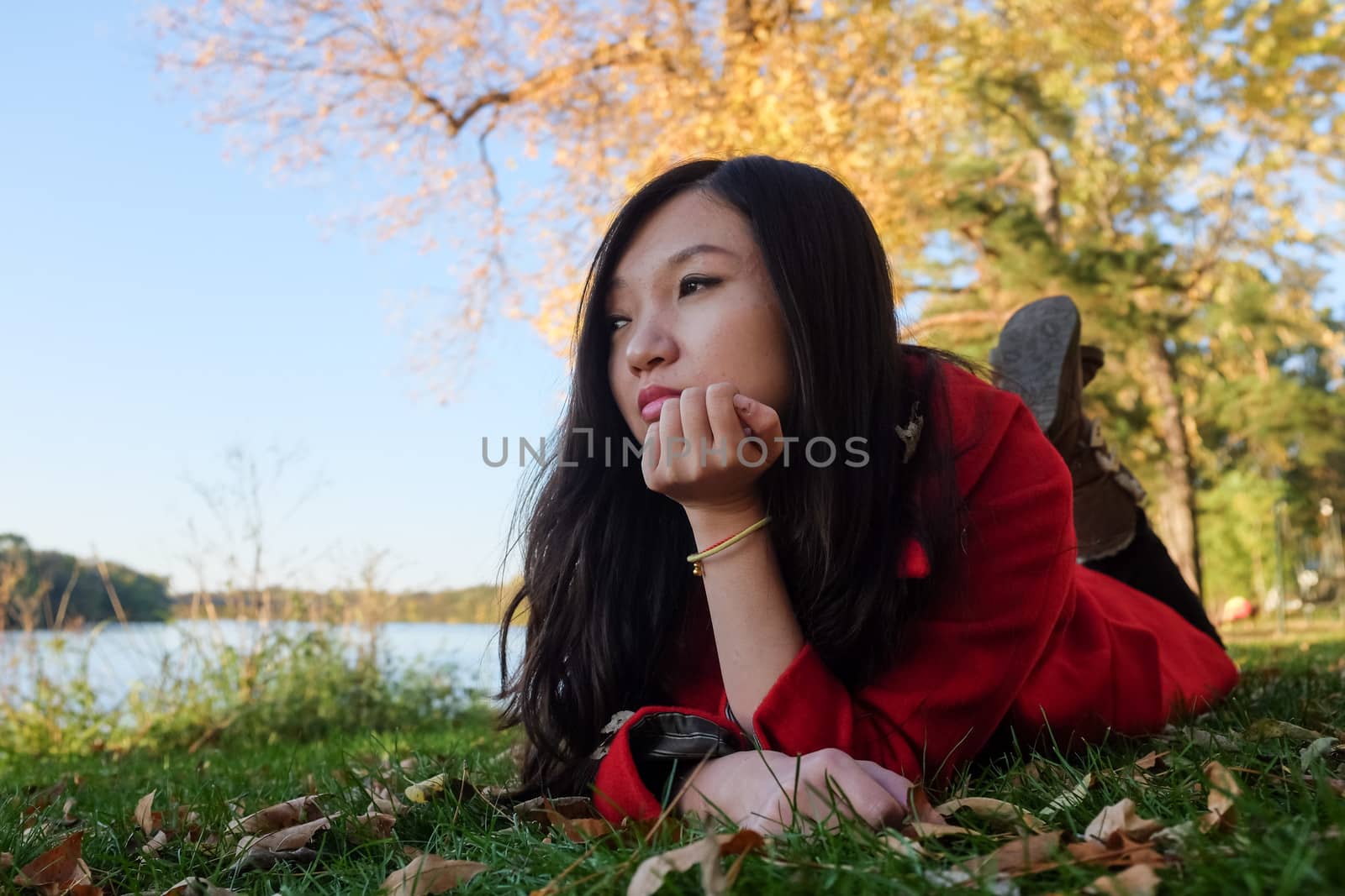 Woman laying on grass by IVYPHOTOS