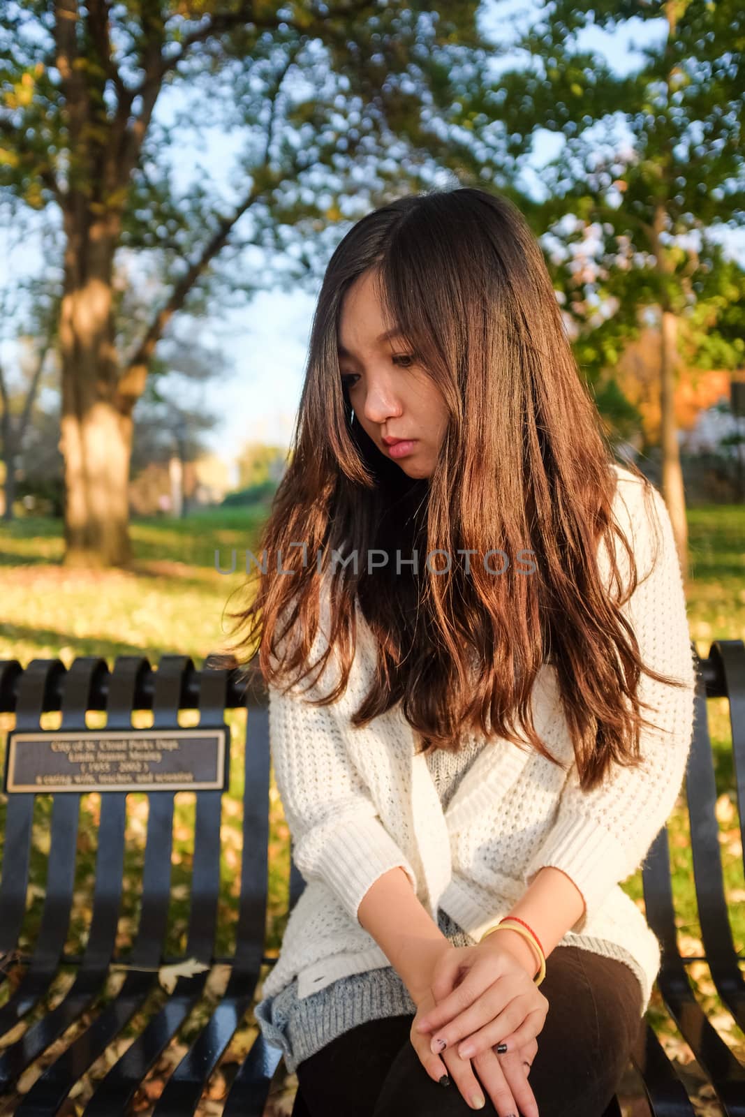lonely young woman sitting on a steel bench