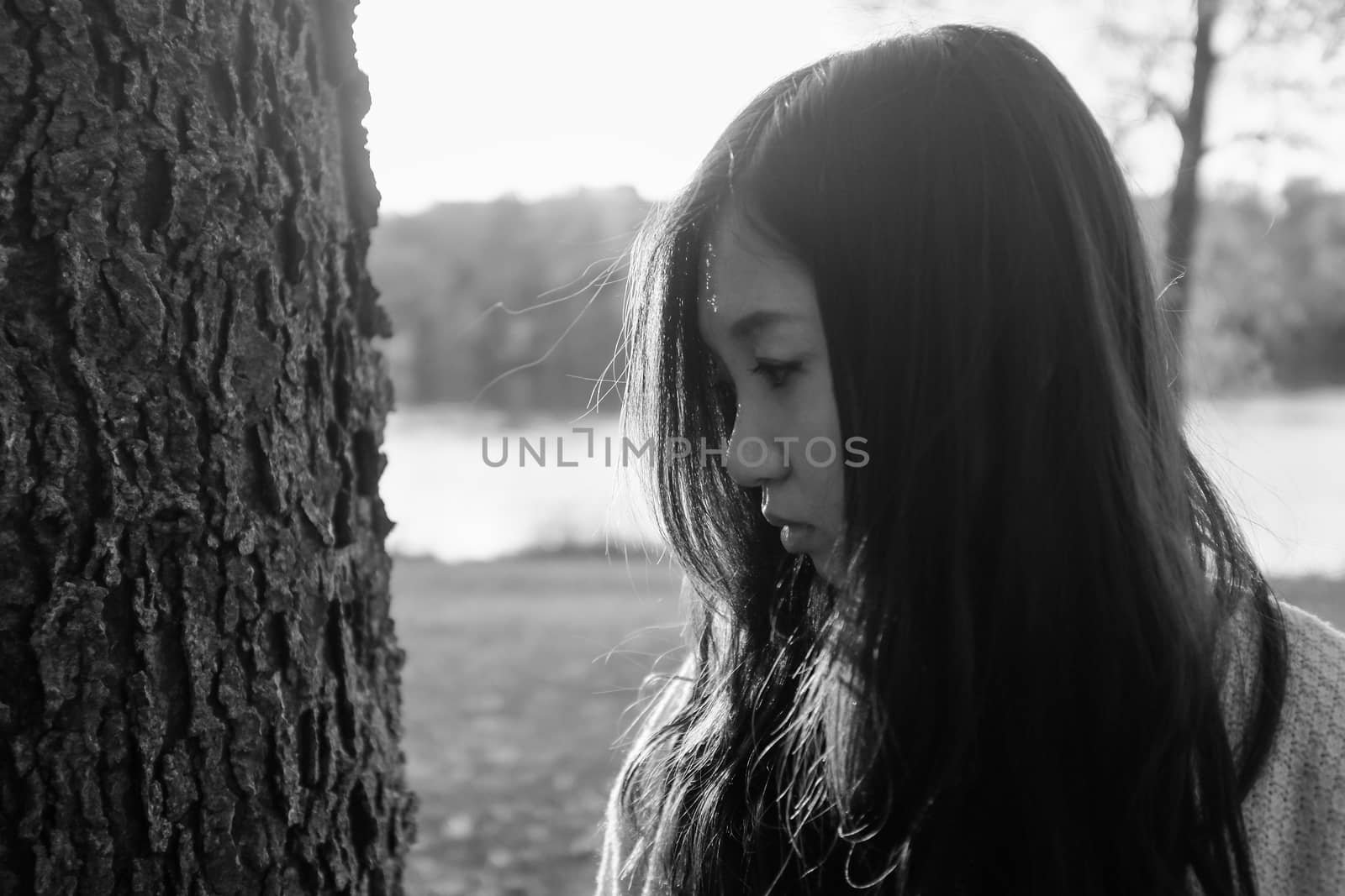 Woman standing next to a tree looking depressed