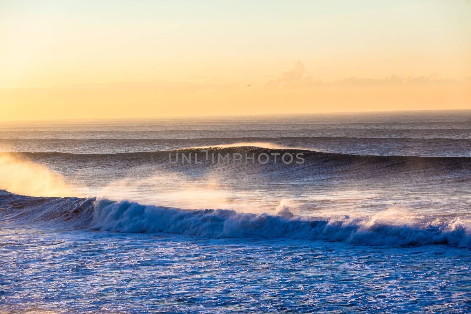 large ocean waves swells crashing breaking towards the beach reefs and sandbars in offshore winds.