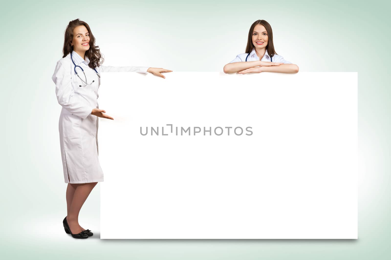 Two young woman doctor holding a blank banner, place for text