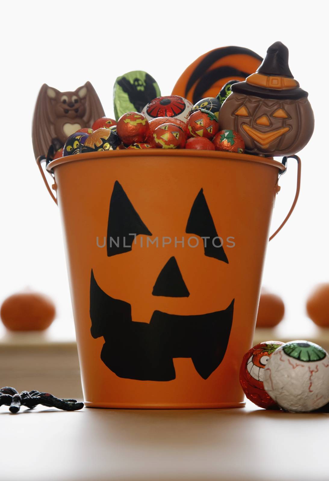 Bucket with Jack O'lantern face filled with sweets by moodboard