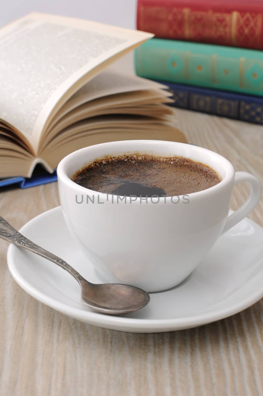 A cup of fragrant black coffee on the table against the background of an open book