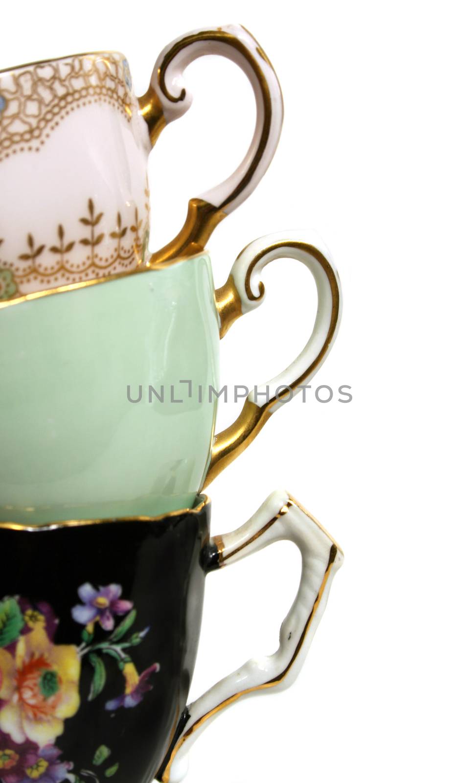 Three antique teacups stacked with gold plated handles. 