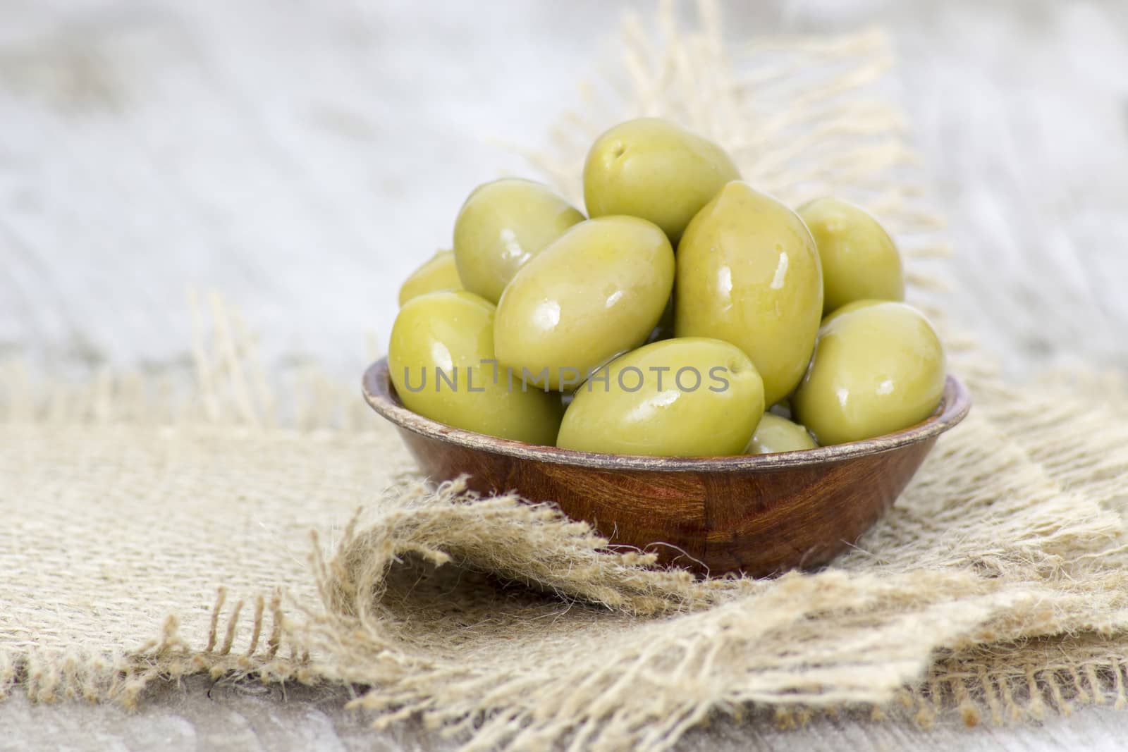 Bowl with freshly whole fresh green olives on a rustic wooden tabletop