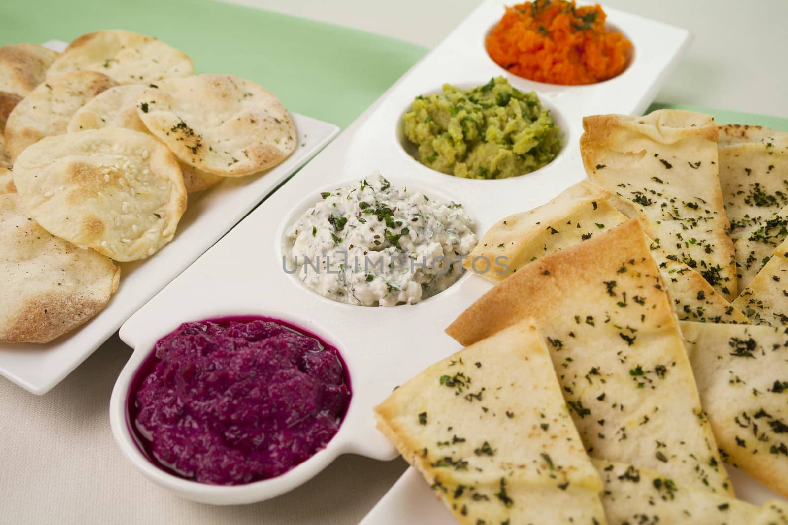 Assorted dips of carrot, cottage cheese and herbs, pea and basil with pita crisps.