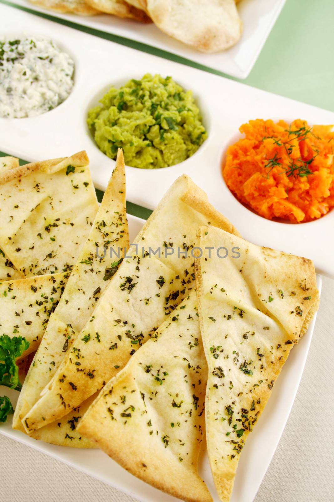 Assorted dips of carrot, cottage cheese and herbs, pea and basil with pita crisps.