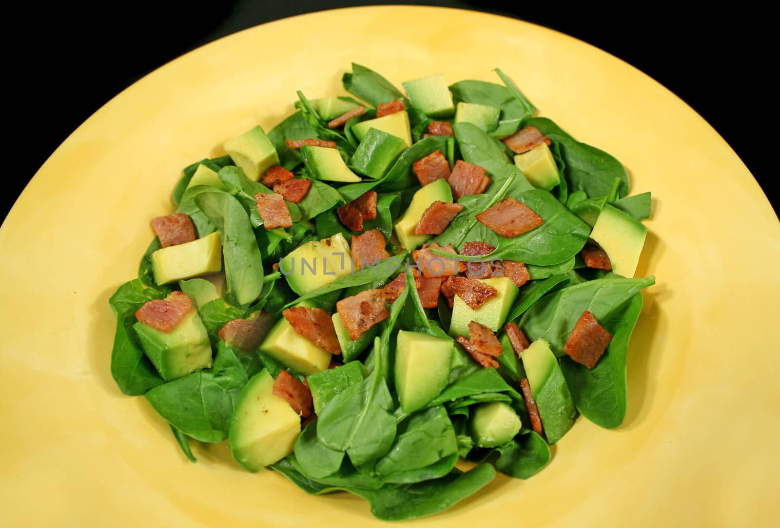 Delightful baby spinach, avocado and bacon salad ready to serve.