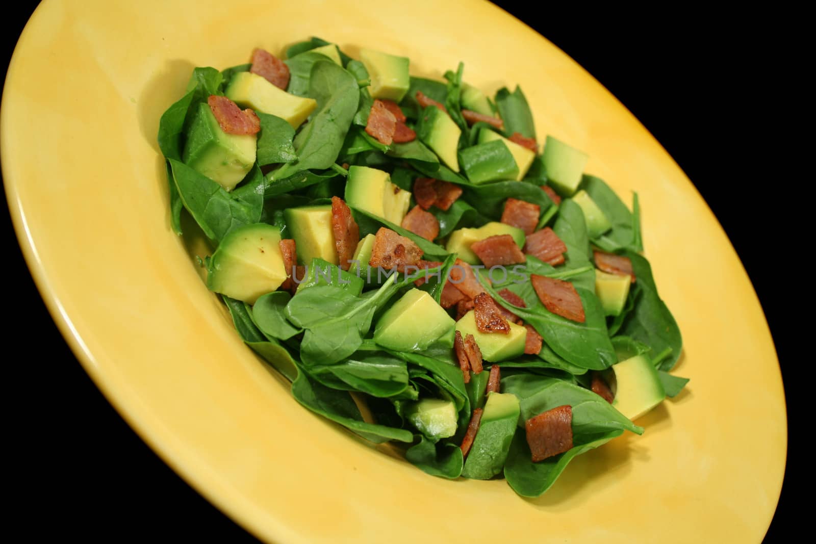 Delightful baby spinach, avocado and bacon salad ready to serve.