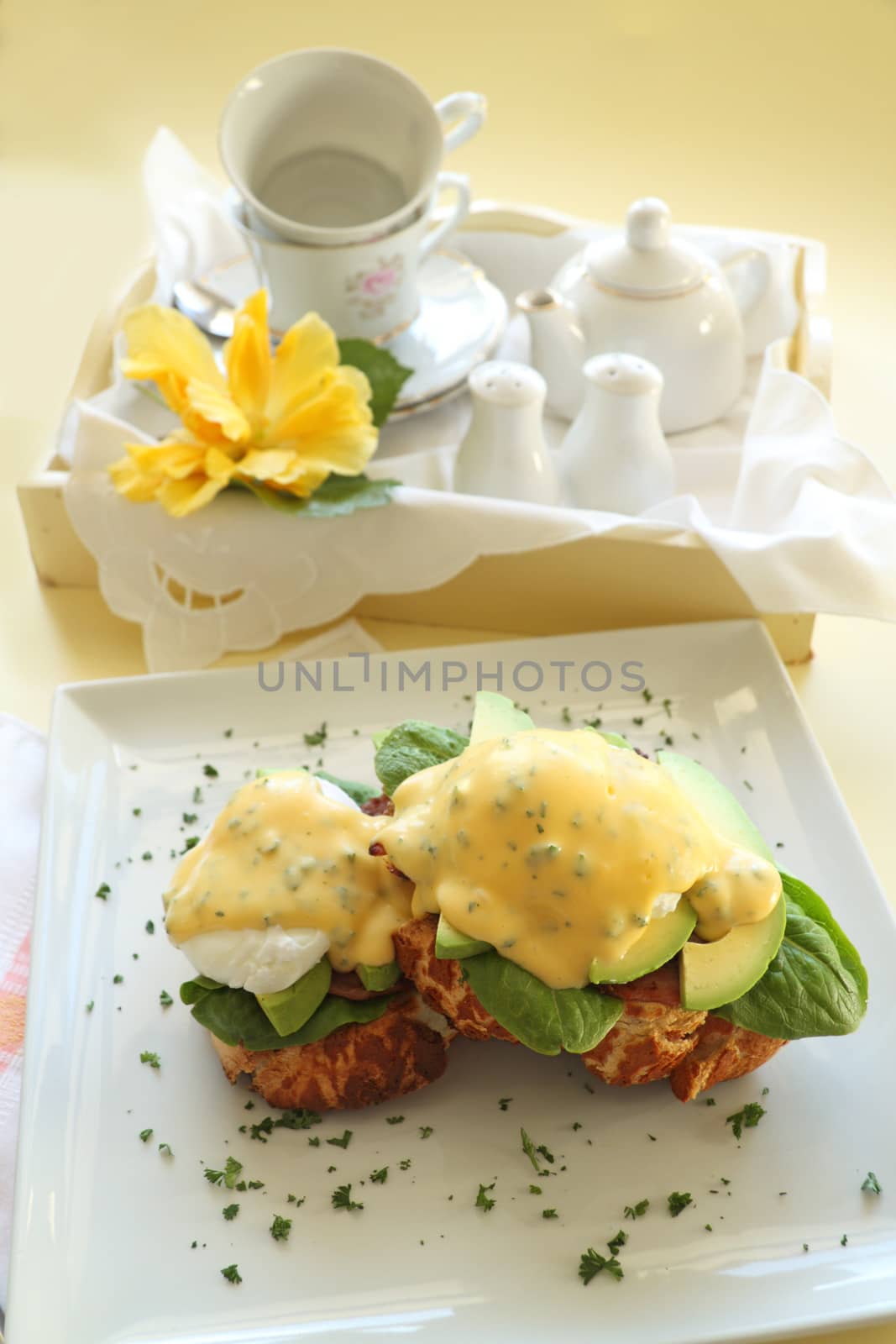 Beautiful eggs benedict with bacon and a rich hollandaise sauce on tiger crust bread.