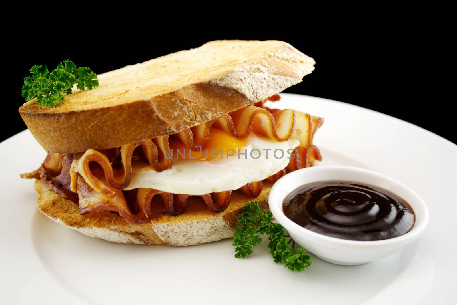 Curled bacon and egg sandwich with BBQ sauce ready to serve.