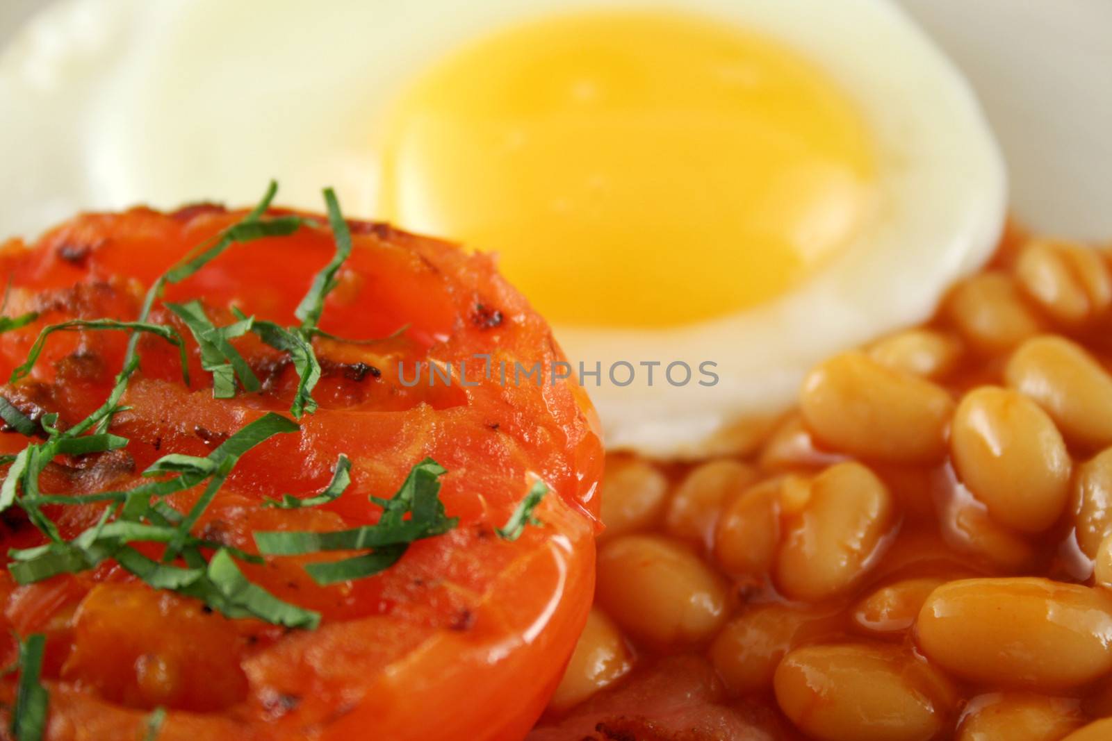 Breakfast of grilled tomato, egg and baked beans.