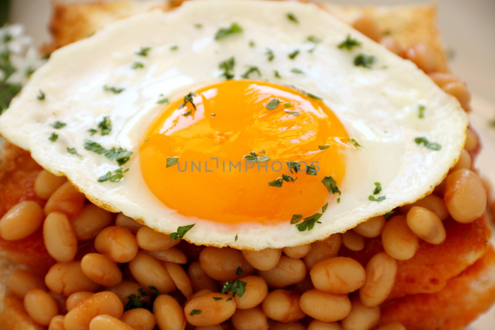 Delicious old fashioned breakfast of a fried egg on a baked beans stack on toast.