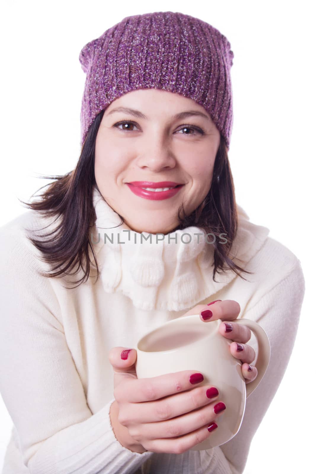Smiling woman in knitted hat holding cup of beverage over white