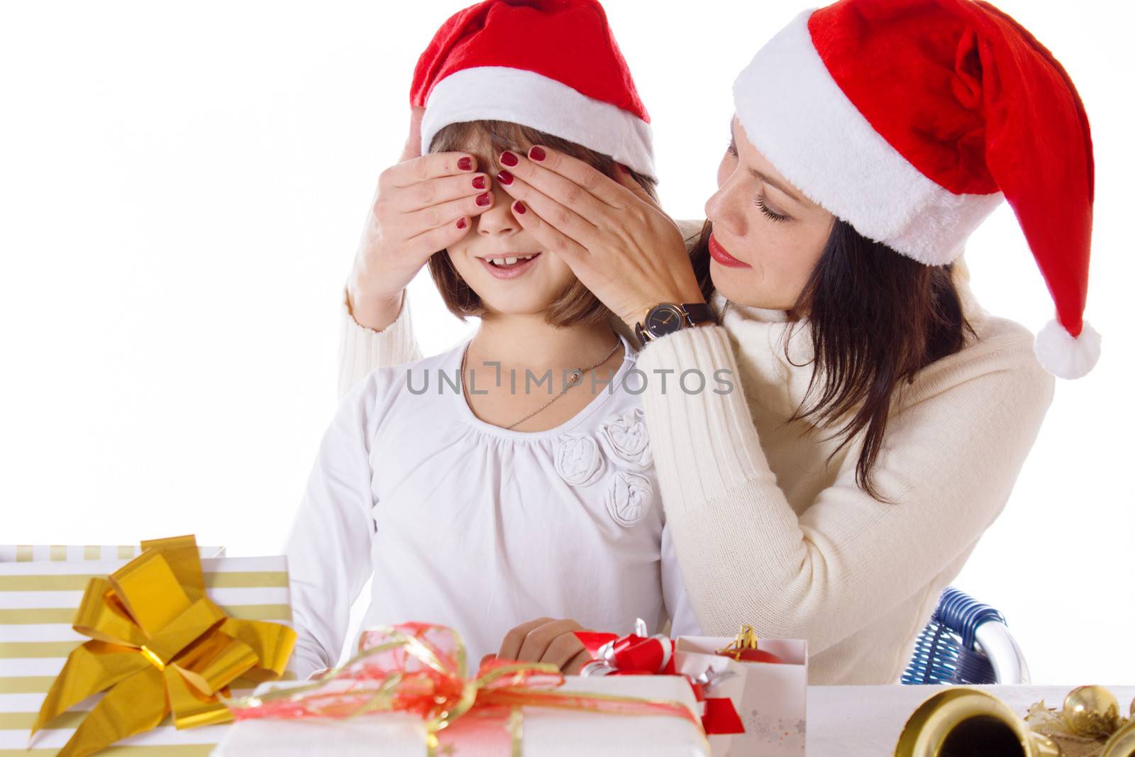 Mother covering daughter eyes with hands hiding Christmas gifts by Angel_a