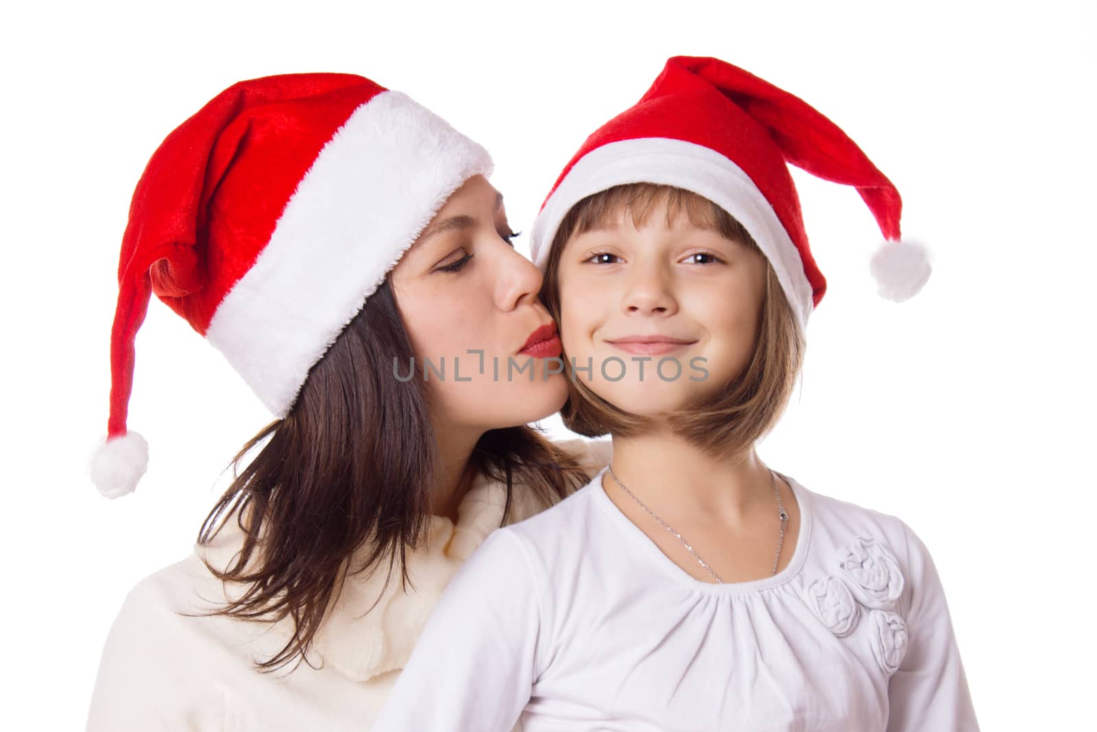Happy mother kissing daughter on cheek in Christmas hat over white