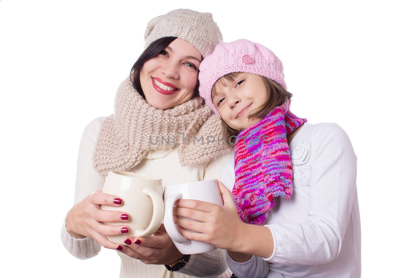 Happy mother and daughter in knitted hats with hot beverages over white