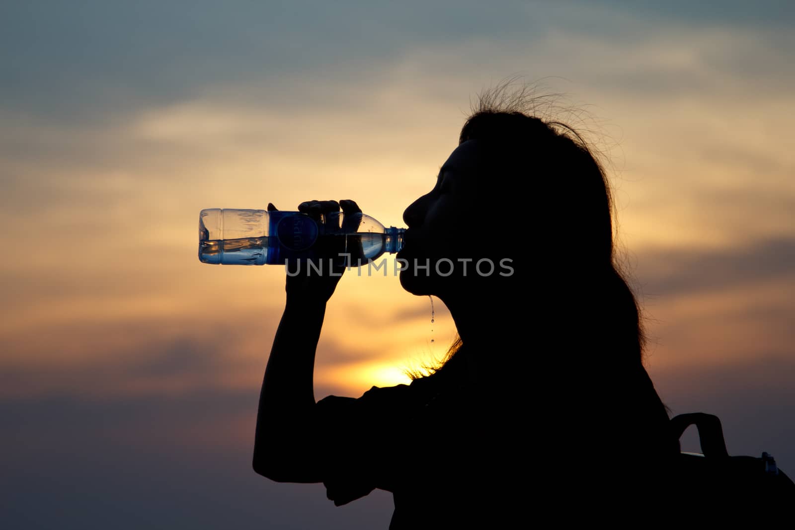 Black silhouette of girl drinking water in the ocean