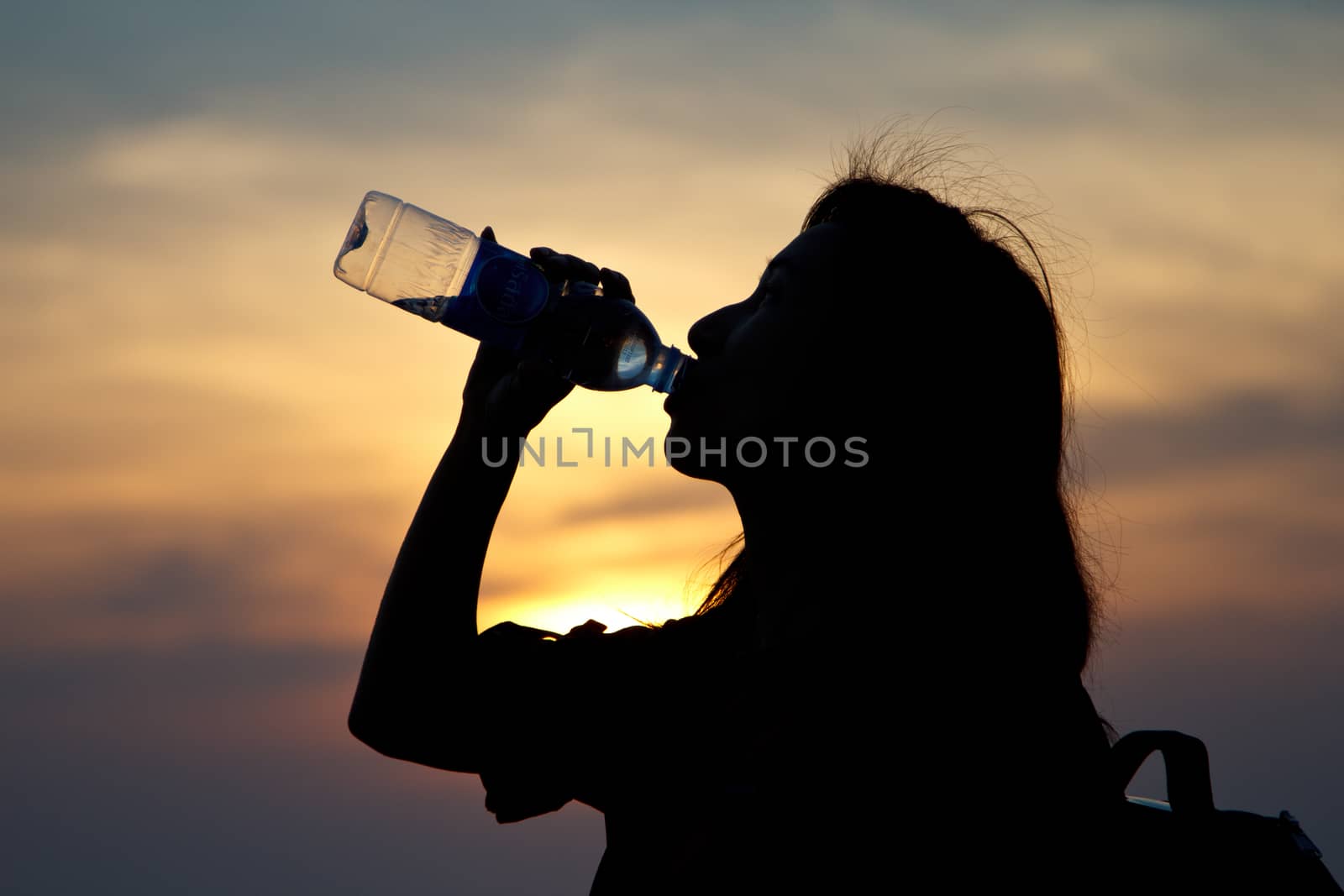 Black silhouette of girl drinking water in the ocean