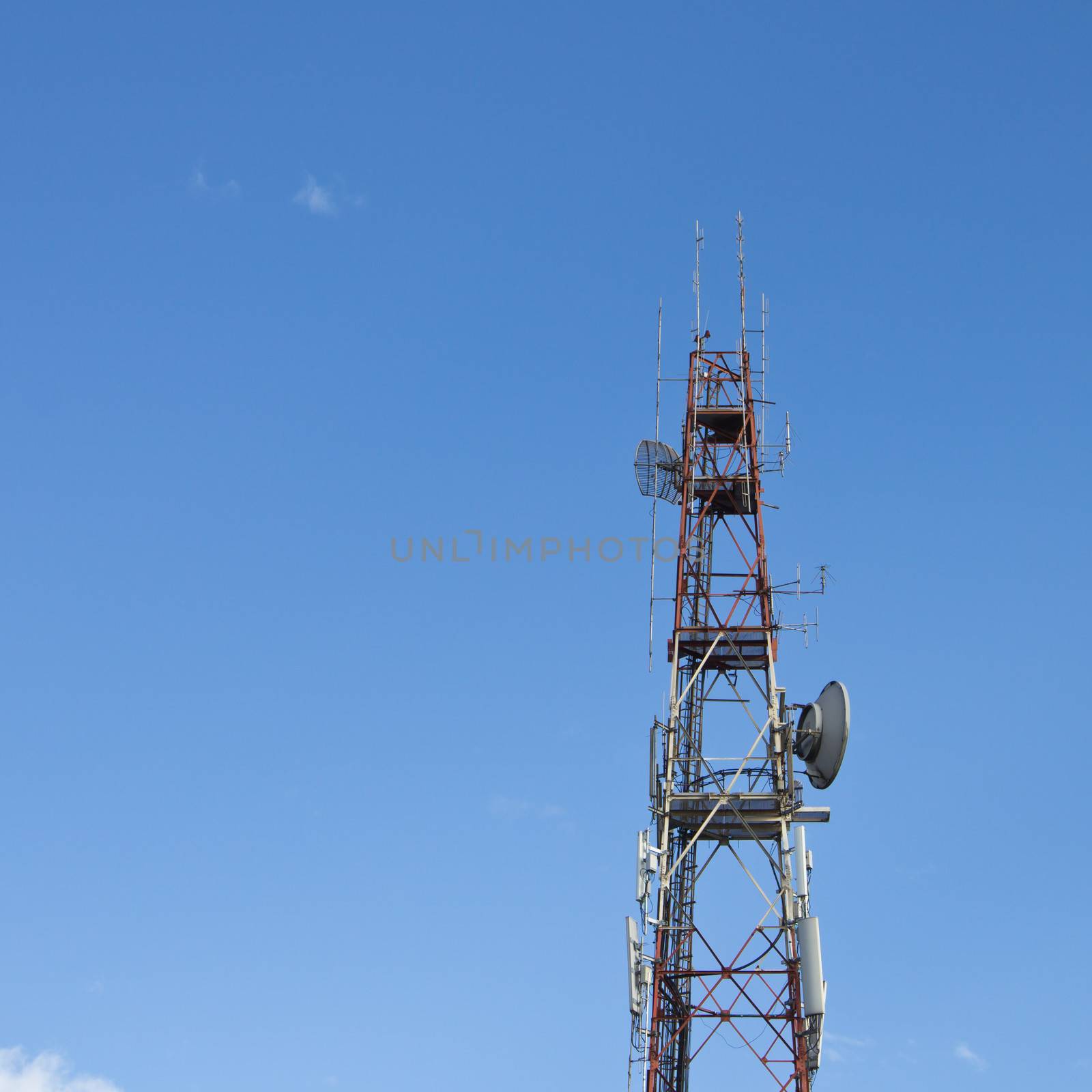 Red and white roof top cellular tower under blue sky