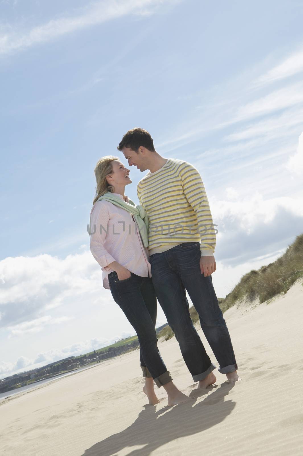 Full length of romantic young couple on beach by moodboard