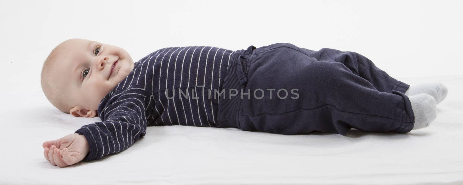 smiling toddler in blue clothing laying down. vertical image
