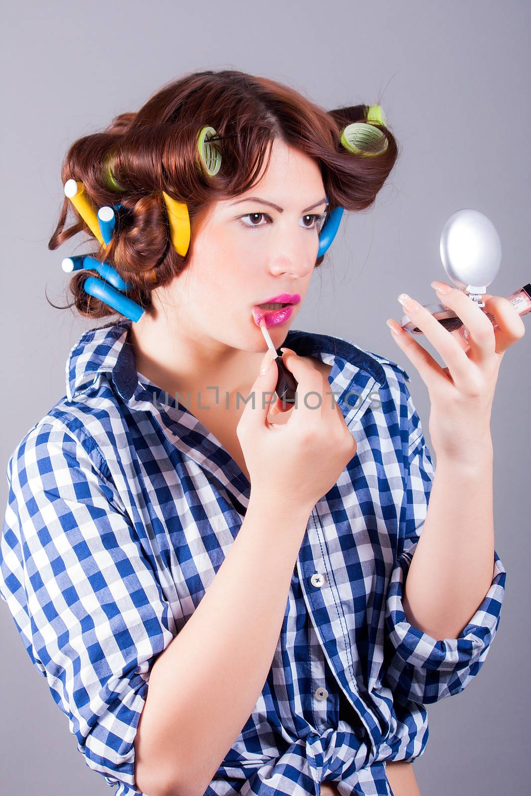 portrait of woman with curlers applying make up
